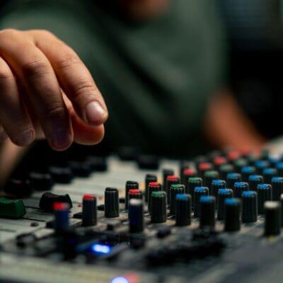 A close-up of an audio mixing console device used by someone working as a sound engineer in a music studio.