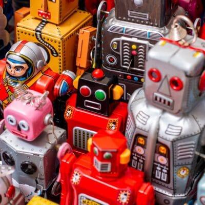 Multiple, colorful vintage tin robot toys in various sizes stand upright, showcasing their retro design.