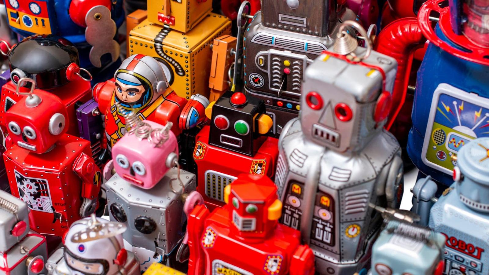Multiple, colorful vintage tin robot toys in various sizes stand upright, showcasing their retro design.