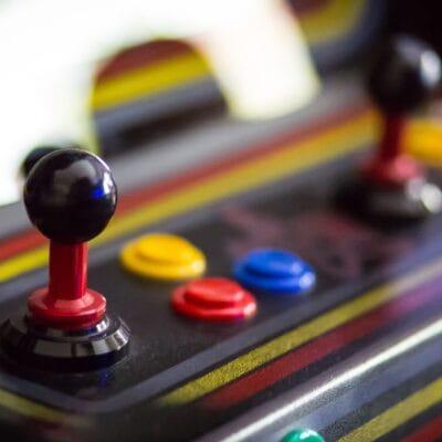 An arcade cabinet with two joy sticks and several buttons. The buttons are different colors.